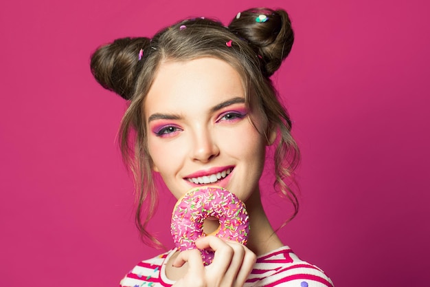 Photo smiling woman holding donut on vivid pink background diet concept