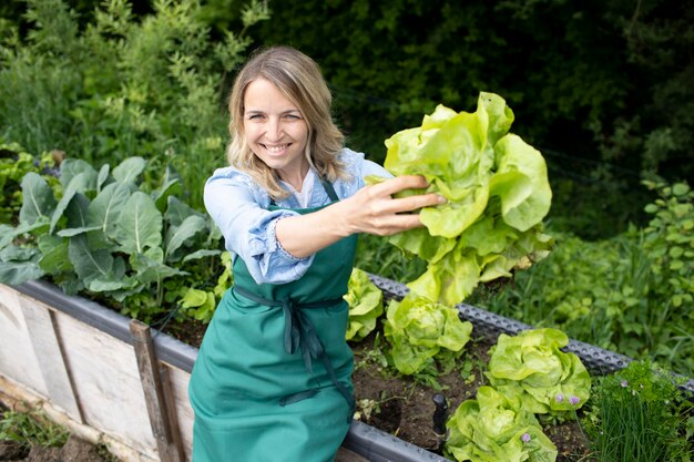 Photo smiling woman holding fresh green plants in garden