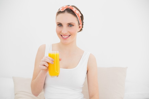 Smiling woman holding a glass of orange juice 