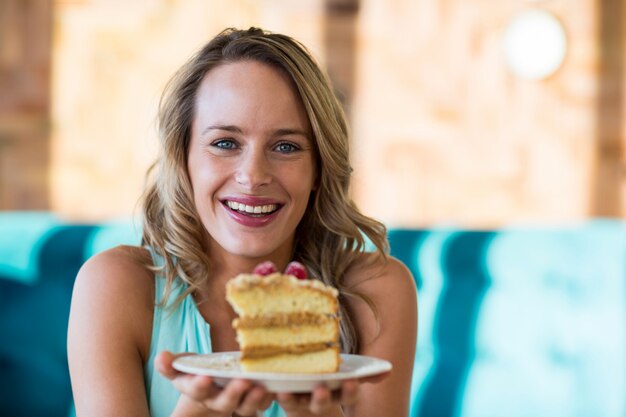 Улыбающиеся женщина, держащая тесто на тарелку