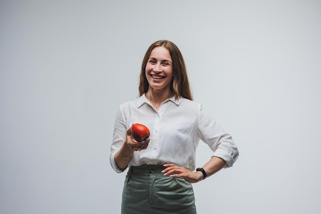 Donna sorridente in possesso di una mela rossa bella bruna in una camicia bianca cibo vegetale sano e vitamine sfondo bianco