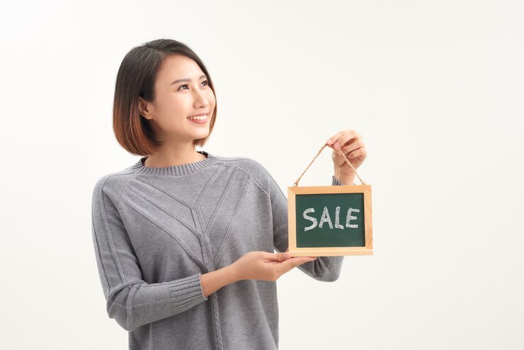 Photo smiling woman holding sale sign isolated over white