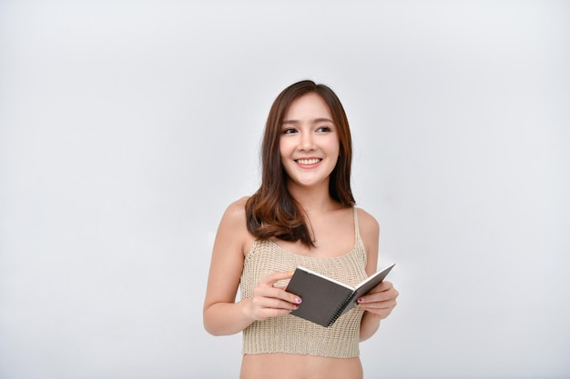 smiling woman holding spiral book against wall