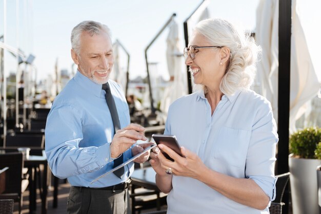 Smiling woman holding telephone in left hand and standing in semi position while feeling happiness