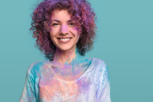 Smiling woman in holi colors in studio