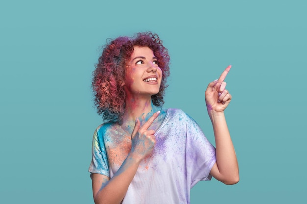 Smiling woman in Holi powder pointing up