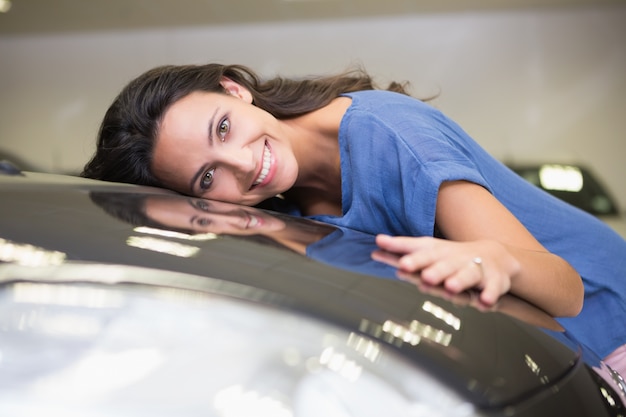 Donna sorridente che abbraccia un'auto nera