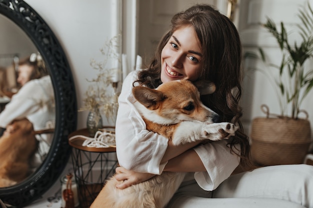 Donna sorridente che abbraccia il corgi davanti allo specchio