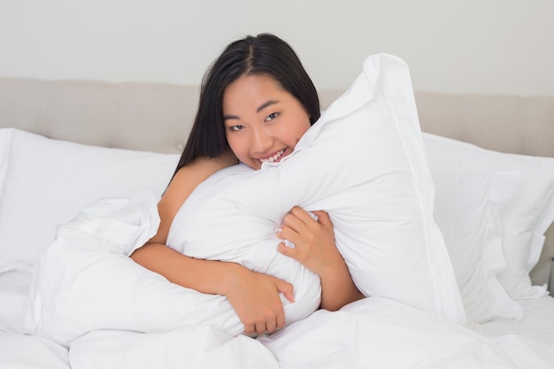 Улыбающаяся женщина обнимает ее подушку
