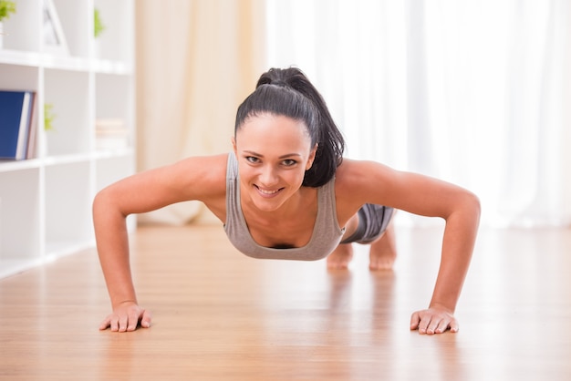 Smiling woman is doing exercises at home.