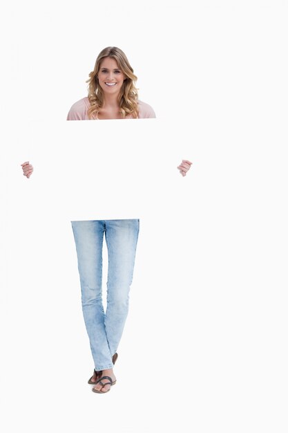 A smiling woman is holding a placard