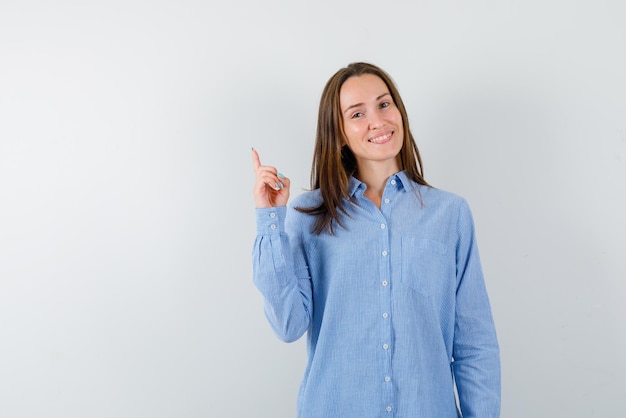 The smiling woman is poinitng up with forefinger   with hand on white background