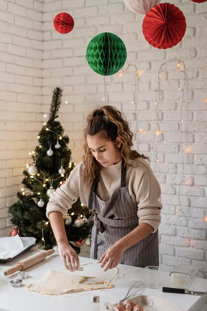 Улыбающаяся женщина на кухне, выпекающая рождественское печенье