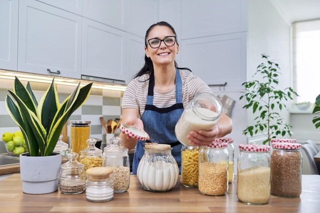 Donna sorridente in cucina con barattoli di cibo immagazzinato