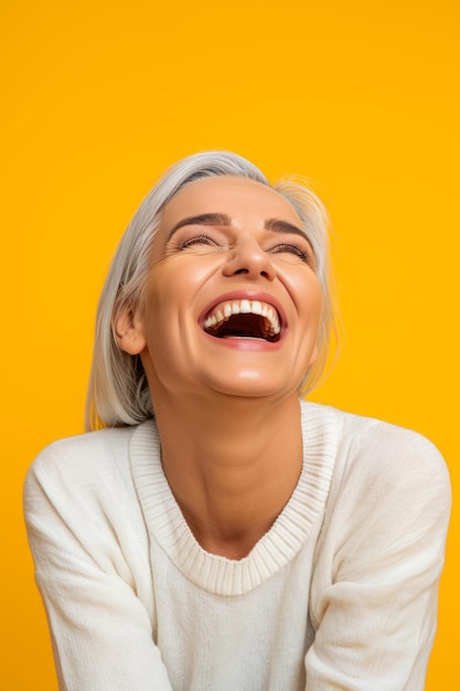 Smiling woman laughing on yellow background