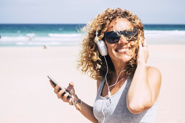 Photo smiling woman listening music at beach