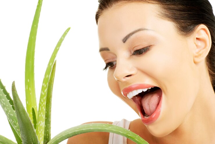 Smiling woman looking at aloe vera against white background