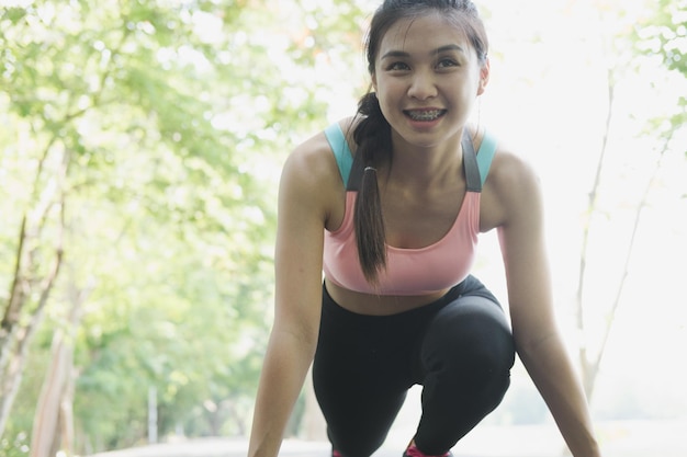 Photo smiling woman looking away while exercising on road by lake