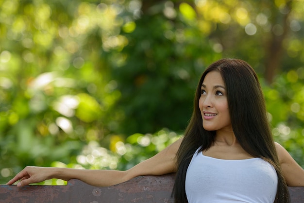 Photo smiling woman looking away while sitting on bench