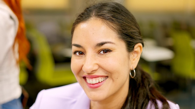 Smiling woman looking at camera sitting in a coworking