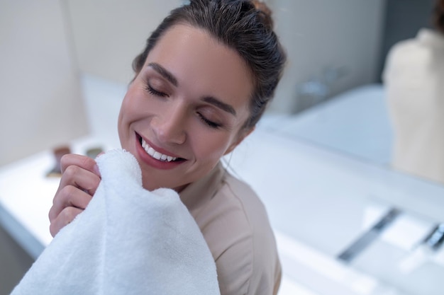 Smiling woman looking contented and holding a fresh towel in hands