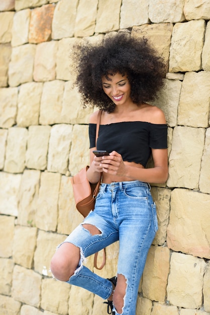 Smiling woman looking at her smart phone outdoors