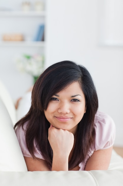 Smiling woman lying on a couch while holding her head with her fist