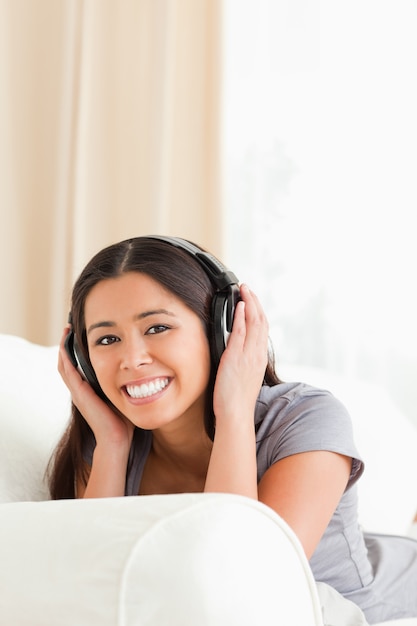 Smiling woman lying on sofa with earphones