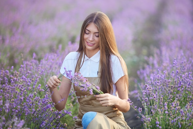 Улыбающаяся женщина делает букет в лавандовом поле