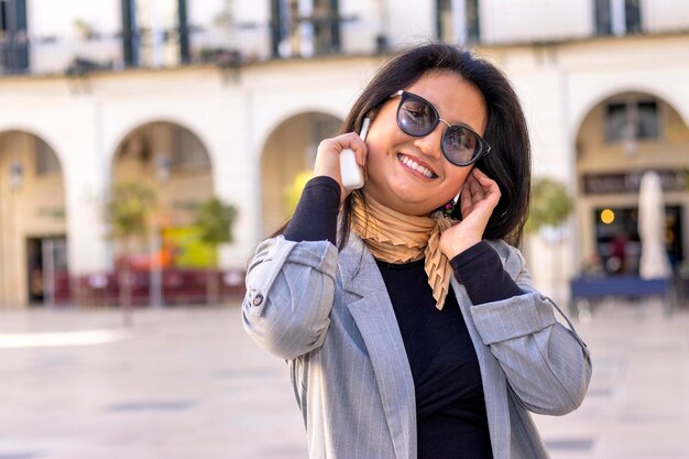 Smiling woman making business call on cell feeling happy about good news outdoors