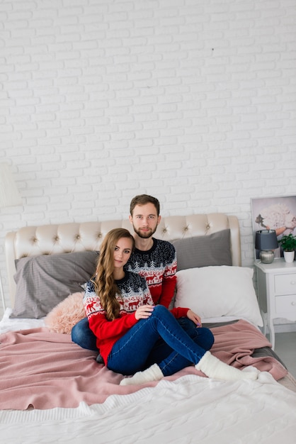 smiling woman and man in Christmas sweaters at home