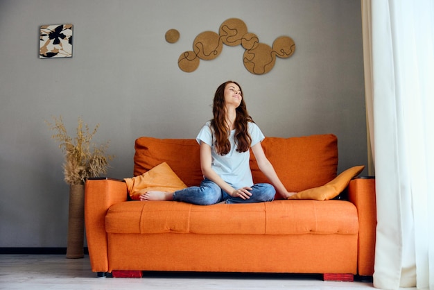 Photo smiling woman on the orange couch in the rest room posing unaltered