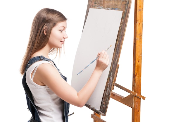 アクリル絵の具でイーゼルの描画に座っている絵筆で笑顔の女性画家