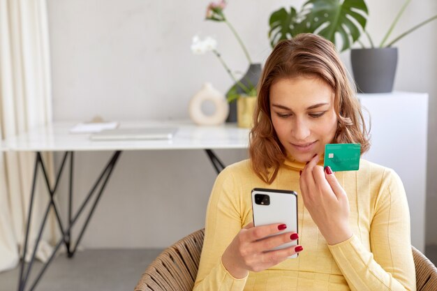 Smiling woman paying by card for online purchase by phone