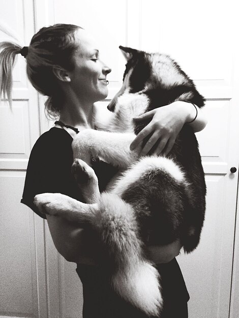 Smiling woman playing with dog at home