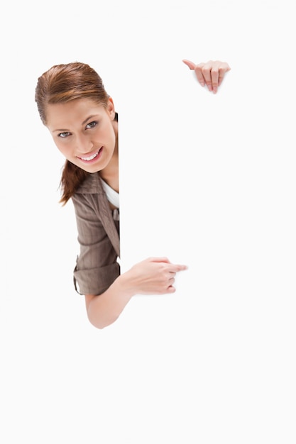 Smiling woman pointing around blank sign