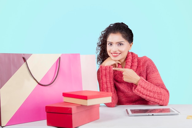 Smiling woman pointing shopping bags on studio