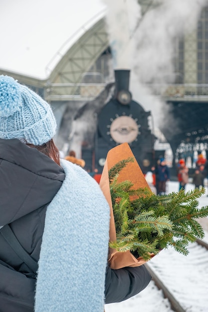 Smiling woman portrait at railway station near old retro steam train