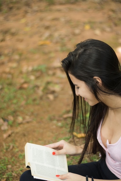 사진 밖에서 앉아서 책을 읽는 미소 짓는 여자