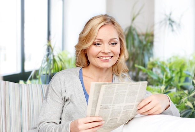 Foto donna sorridente che legge il giornale a casa