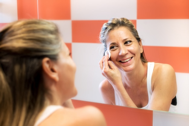 Smiling woman removing makeup