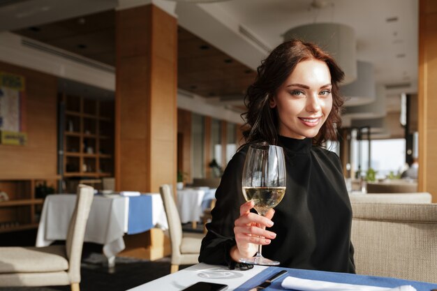 ワイングラスとレストランで笑顔の女性