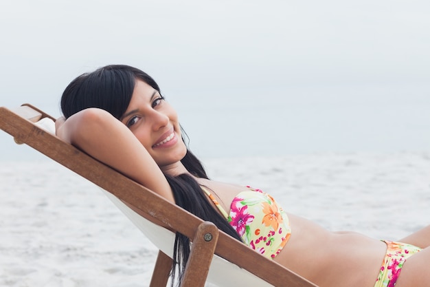 Smiling woman resting on deck chair