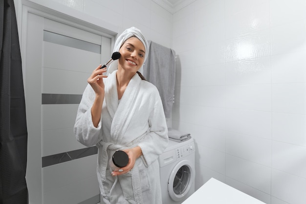 Smiling woman in robe doing makeup