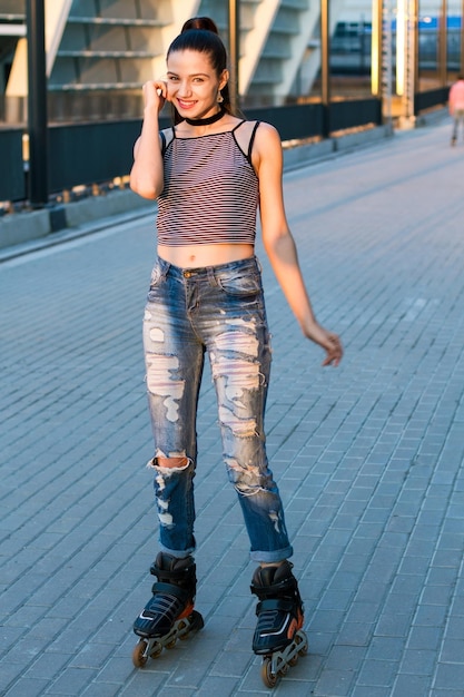 Smiling woman on rollerblades girl on urban background sporty and beautiful