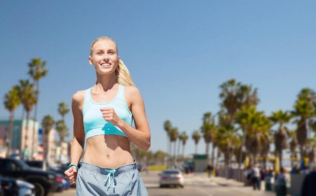 Photo smiling woman running at summer over venice beach