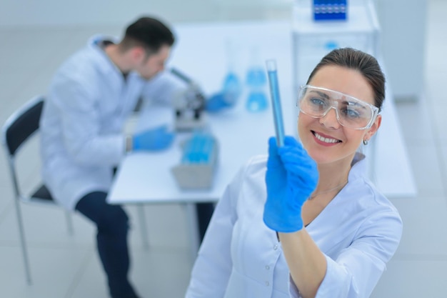 Smiling woman scientist looking at the tube with the results of the analysis