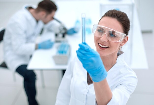 Smiling woman scientist looking at the tube with the results of the analysis