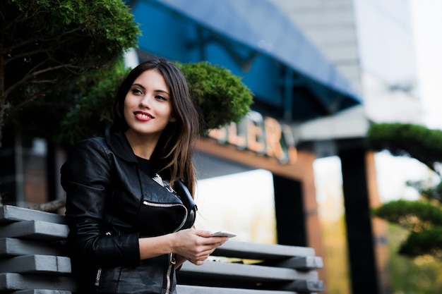 Smiling woman sending sms on the street