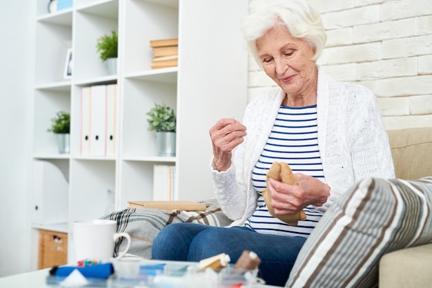 Smiling woman sewing toy at home